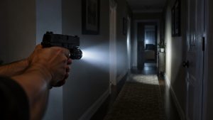 Pistol with a weapon light illuminating a dark hallway